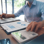 Homme utilisant une calculatrice et des graphiques financiers.