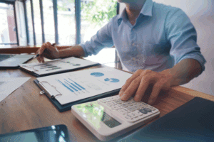 Homme utilisant une calculatrice et des graphiques financiers.