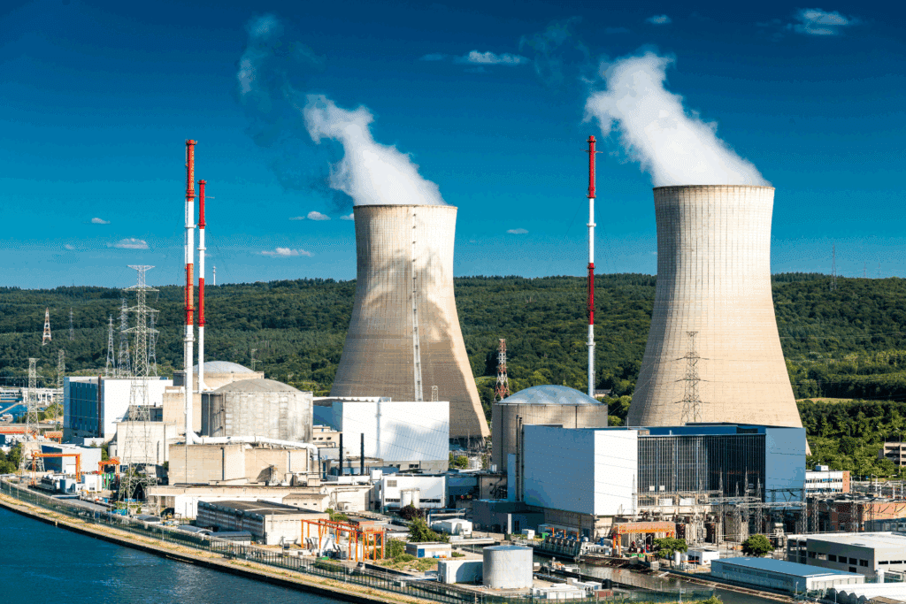 Centrale nucléaire avec cheminées fumantes et forêt.