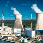 Centrale nucléaire avec cheminées fumantes et forêt.