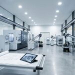 Atelier industriel moderne avec robots, machines-outils et plans d'implantation posés sur une table