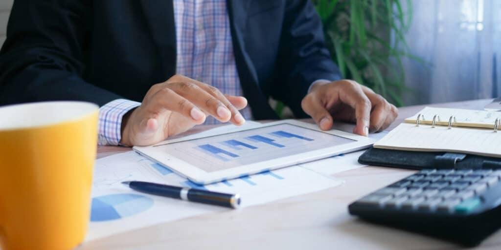 Homme travaillant sur une tablette avec graphiques.