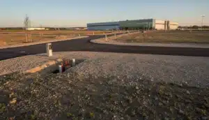 Terrain industriel viabilisé avec voirie neuve et halle moderne en arrière-plan